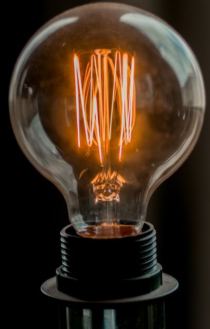 Photo of an iridescent light bulb with lighted elements inside, surrounded by a black plastic base. 